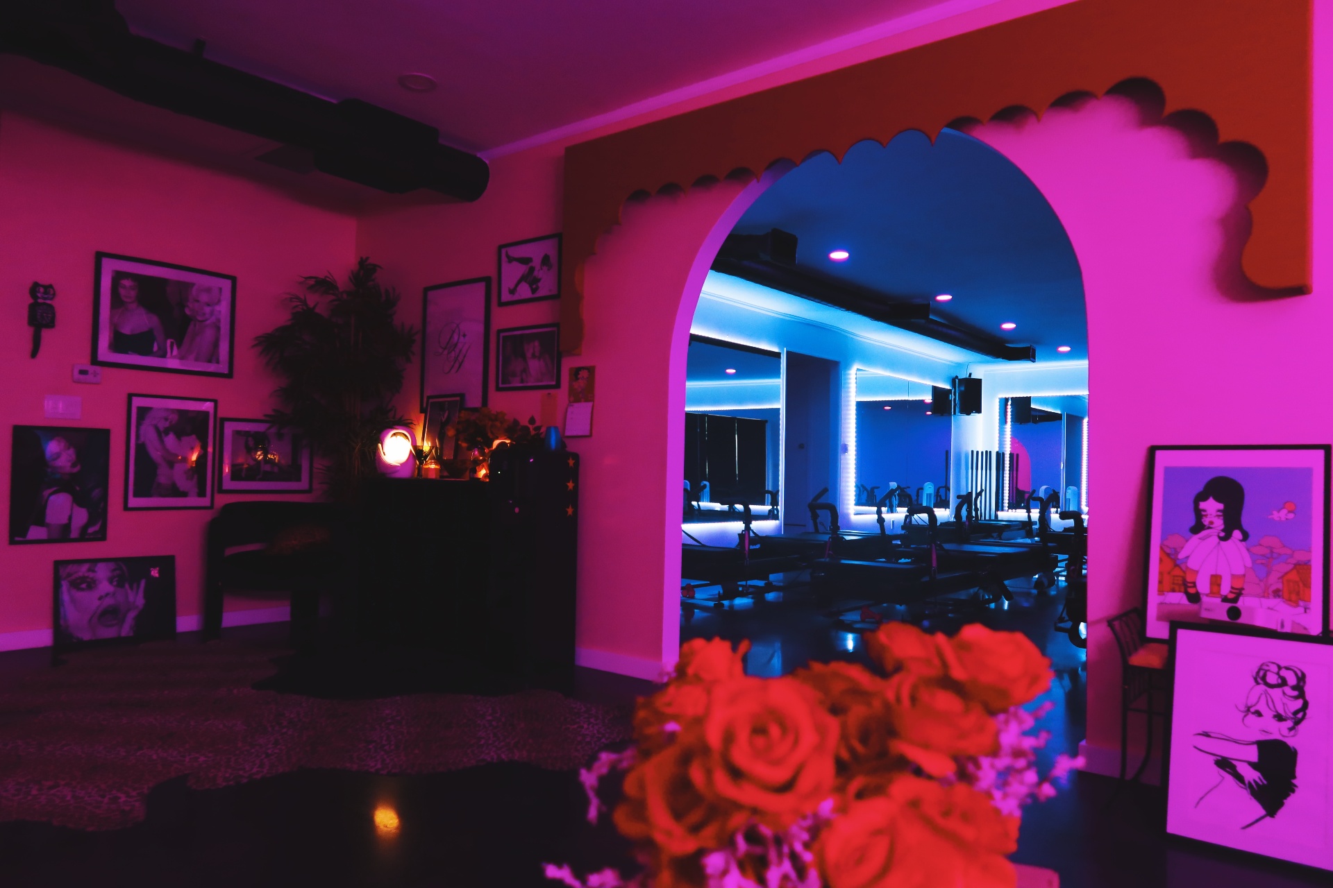 DollHouse Pilates studio with X-Former reformers under purple neon, framed by a pink archway